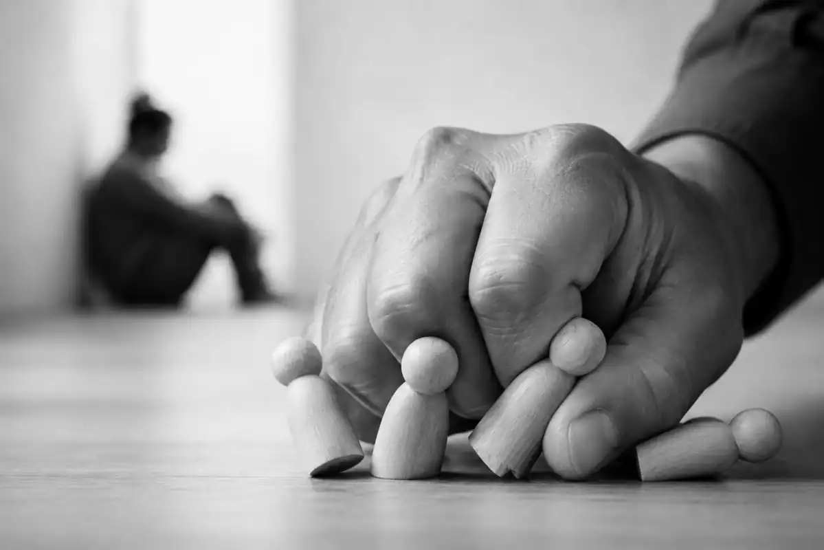 Figurines de salariés renversées et écrasées par une main, symbole de domination au travail